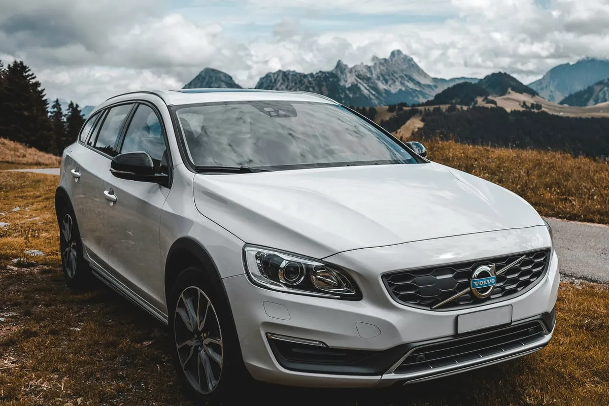 Weißer Volvo V60 Cross Country schräg von vorn, dahinter Berge
