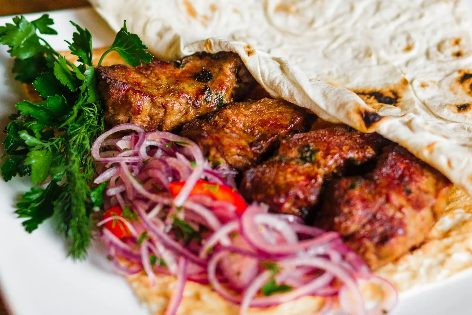 Kebab vom Grill mit Lavaş, roten Zwiebeln und Petersilie